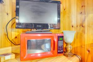 a red microwave with a tv on top of it at Sevierville Studio Cabin Rental with Private Hot Tub in Sevierville