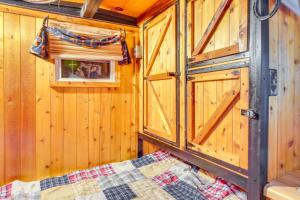 a bedroom with wooden walls and a bed and a window at Sevierville Studio Cabin Rental with Private Hot Tub in Sevierville