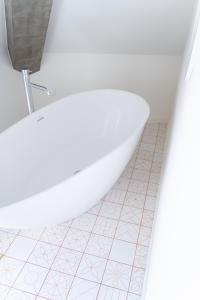 uma banheira branca na casa de banho com piso em azulejo em A'MAR by Alojamento Ideal em Póvoa de Varzim