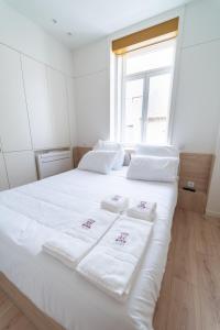 Una cama blanca con toallas blancas encima. en A'MAR by Alojamento Ideal en Póvoa de Varzim