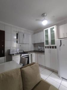 a kitchen with white cabinets and a couch in it at Apartamento ao lado Praça Central in Poços de Caldas
