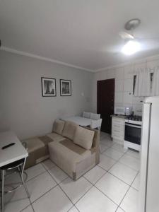 a living room with a couch and a kitchen at Apartamento ao lado Praça Central in Poços de Caldas