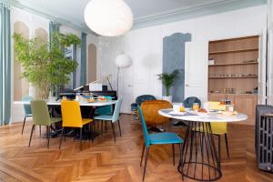 a dining room with two tables and colorful chairs at La Parenthèse Fléchoise, Chambre Agathe in La Flèche