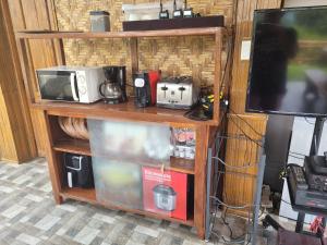 a room with a shelf with a microwave and a tv at Luxury Bahay Kubo in a Farm Near Tagaytay in Tagaytay