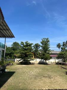 een tuin met twee bomen en een gebouw bij Safiyya Homestay in Kota Bharu