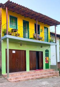 a yellow and green house with a balcony at Hostel Zig Zag Suítes in Lençóis