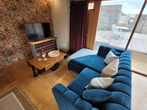 a living room with a blue couch and a tv at The Manor Pen in Lenham