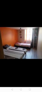 2 camas en una habitación con pared de color naranja en Nid douillet, en Genilac