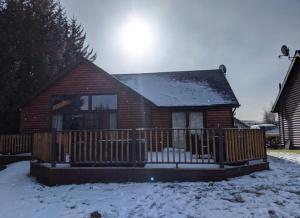 a house with a wooden fence in the snow at Na Craigean Lodge in White Bridge