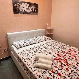 a bedroom with a bed with a floral bedspread and two towels at Al Borgo in Avola