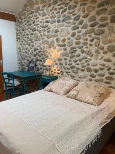 een slaapkamer met een stenen muur, een bed en een tafel bij Vercors en Vert , chambres d'hôtes de charme in Saint-Romans