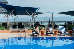 two people sitting in chairs next to a swimming pool at Acacia Premier Hotel in Kisumu