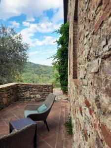 eine Terrasse mit 2 Stühlen und einer Steinmauer in der Unterkunft Borgo Livernano - Farmhouse with pool in Radda in Chianti