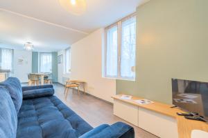 un soggiorno con un divano blu e una TV di Le Cottage du Louvre a Lens