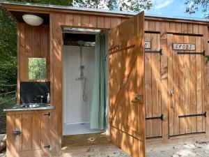 une grande cabane en bois avec douche et lavabo dans l'établissement Lodge Dormir au chant des loups, à Sury-aux-Bois