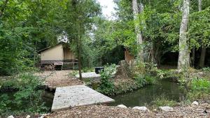 une maison avec un pont sur un ruisseau dans les bois dans l'établissement Lodge Dormir au chant des loups, à Sury-aux-Bois