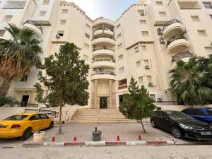a building with two cars parked in front of it at fatimides appartement in La Marsa