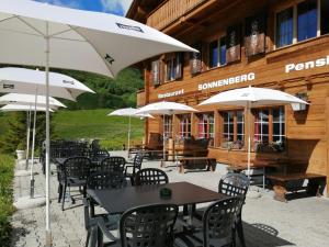 a group of tables and chairs with umbrellas in front of a building at Sonnenberg Hostel and Dormitories in Mürren