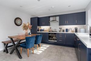 a kitchen with a wooden table and blue cabinets at The Nest - 15 min walk to Craigavon Area Hospital in Craigavon