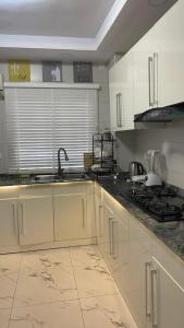 La cuisine est équipée de placards blancs, d'un évier et d'une cuisinière. dans l'établissement Gerdette Luxury Apartment, à Lagos