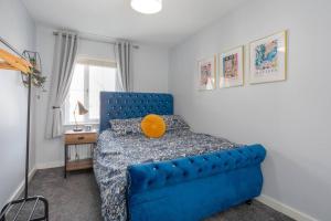 um quarto com uma cama azul e uma almofada laranja em The Nest - 15 min walk to Craigavon Area Hospital em Craigavon