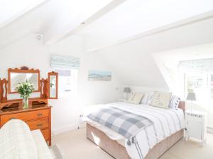 a white bedroom with a bed and a dresser at Marine Cottage in Salcombe