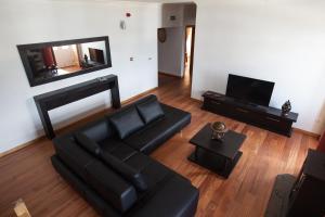a living room with a black couch and a television at Pico da Saudade in Prainha de Baixo
