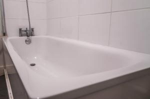 a white bath tub in a white tiled bathroom at Wonderful cozy double room-Only Room in London