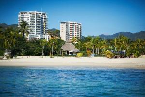 - une plage avec deux grands bâtiments et des palmiers dans l'établissement Oceanview Oasis in La Cruz, à La Cruz de Huanacaxtle
