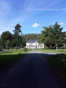 uma grande casa branca sentada no topo de uma estrada em L'Atelier à l'orée des bois em Saint-Pierre-sur-Dives