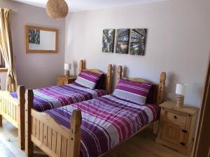 two beds in a bedroom with purple sheets at Lochside Lodge in White Bridge