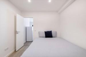 リスボンにあるCozy and modern flat in Lisbonの白いベッドルーム(大きな白いベッド1台、オープンドア付)