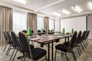 einen Konferenzraum mit langen Tischen und Stühlen in der Unterkunft Ramada by Wyndham Halle-Leipzig in Halle an der Saale
