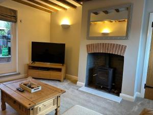 a living room with a fireplace and a television at Honeysuckle Cottage in Mountsorrel