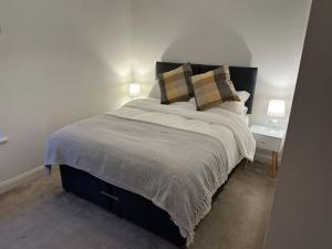 a bedroom with a large bed with two tables and two lamps at Honeysuckle Cottage in Mountsorrel