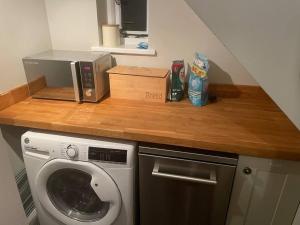 una encimera de cocina con lavadora y microondas en Honeysuckle Cottage, en Mountsorrel