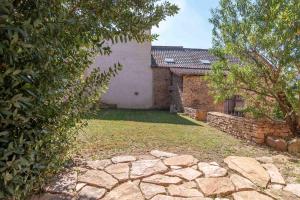 a yard with a brick building and a stone wall at Le Grand Pressoir - Grande maison avec jardin in Nanton