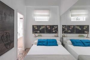 two beds with blue pillows in a white room at Lujoso apartamento con patio en Triana Sevilla in Seville