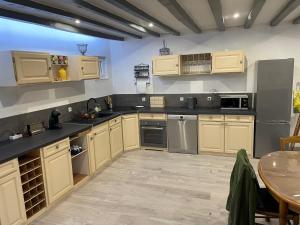 a large kitchen with white cabinets and a table at Gîte La Baz en centre-ville d'un village du Perche - La Bazoche-Gouet in La Bazoche-Gouet