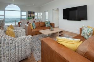 a living room with couches and a flat screen tv at Absolute Ocean Boutique Guesthouse in Hermanus