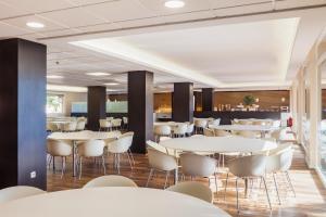 une salle à manger avec des tables et des chaises blanches dans l'établissement Checkin Montserrat, à Collbató