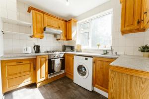 - une cuisine avec des placards en bois et un lave-linge/sèche-linge dans l'établissement Leyton Comfy Double rooms - 50, à Londres