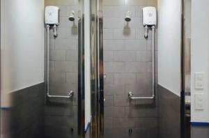 a shower stall in a bathroom with two mirrors at Tales Khaosan (Cafe & Hostel) in Bangkok