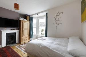 a bedroom with a white bed and a fireplace at Three Bedroomed Victorian Family House, Garden in Brighton & Hove