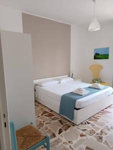 a white bedroom with a bed and a chair at Mare a Sud in Villaggio Azzurro