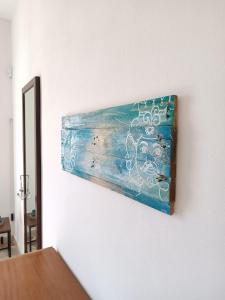 a painting hanging on a white wall at Mare a Sud in Villaggio Azzurro