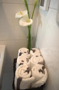 Un montón de toallas en un baño con un jarrón con una flor en Central Apartment Adria, en Rovinj