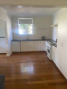 a kitchen with white cabinets and a wooden floor at Golden Street Cottage in West Wyalong +10 photos