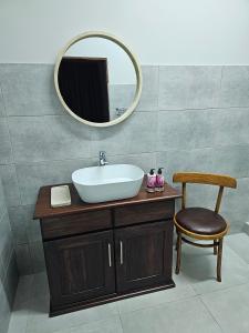 een badkamer met een wastafel, een spiegel en een stoel bij 2 Owls Guesthouse in Potchefstroom
