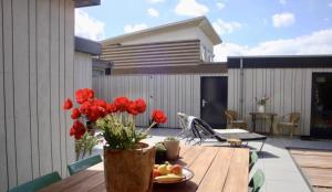a patio with a wooden table with red flowers in a vase at White Sand Beach in Bergen aan Zee +7 photos